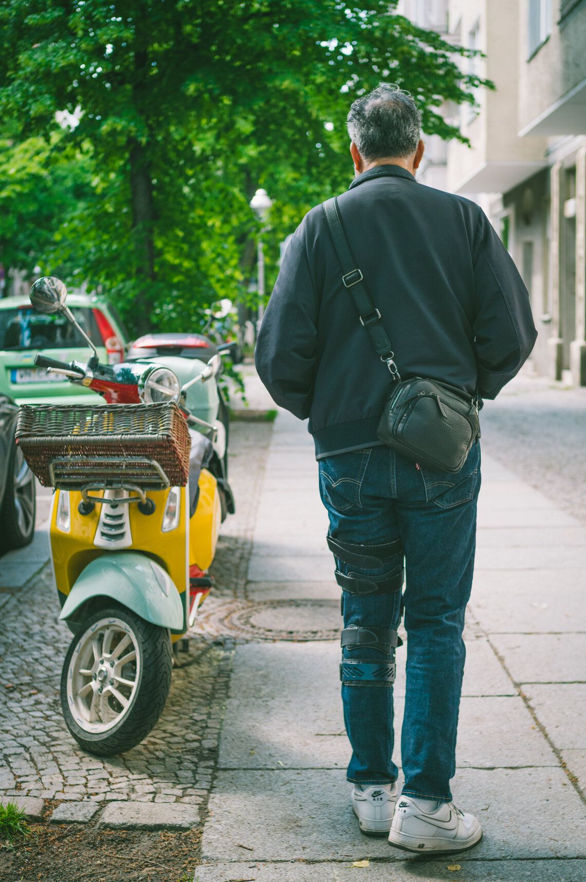 Mann läuft durch eine Berliner Seitenstraße und trägt die Oberwerth KIKI als kompakte Crossbody-Tasche im Alltag.