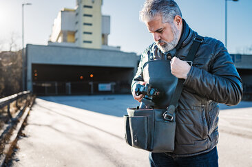 Fotograf greift unterwegs auf eine Kamera aus der Oberwerth Little William Umhängetasche zu