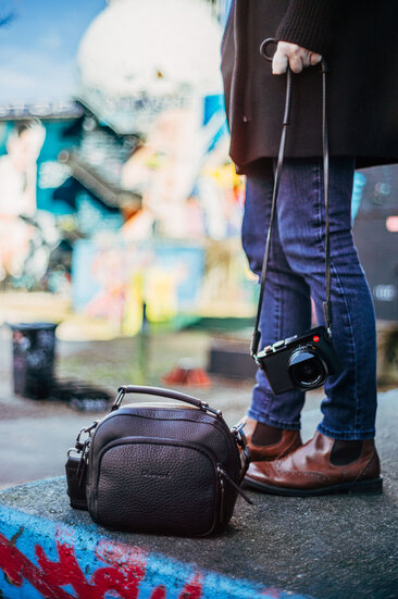 Die Oberwerth KIKI aus schwarzem Leder zusammen mit einer Leica Kamera in urbaner Umgebung bei einem Street-Photography-Einsatz.