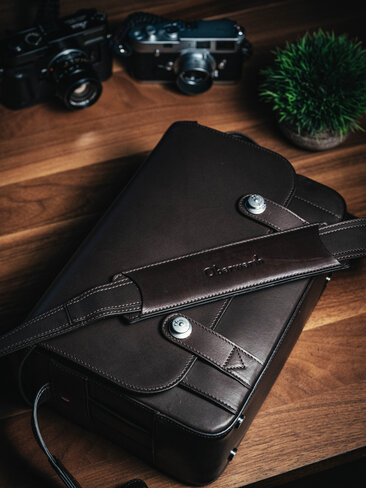 Oberwerth Signature Bag L aus Leder auf Holztisch mit Leica Kameras im Hintergrund